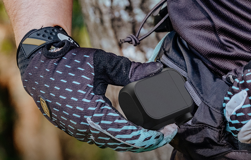 Rowerzysta w rękawiczce wkłada kompaktową czarną pompkę Cycplus do małej kieszeni torby biodrowej.
